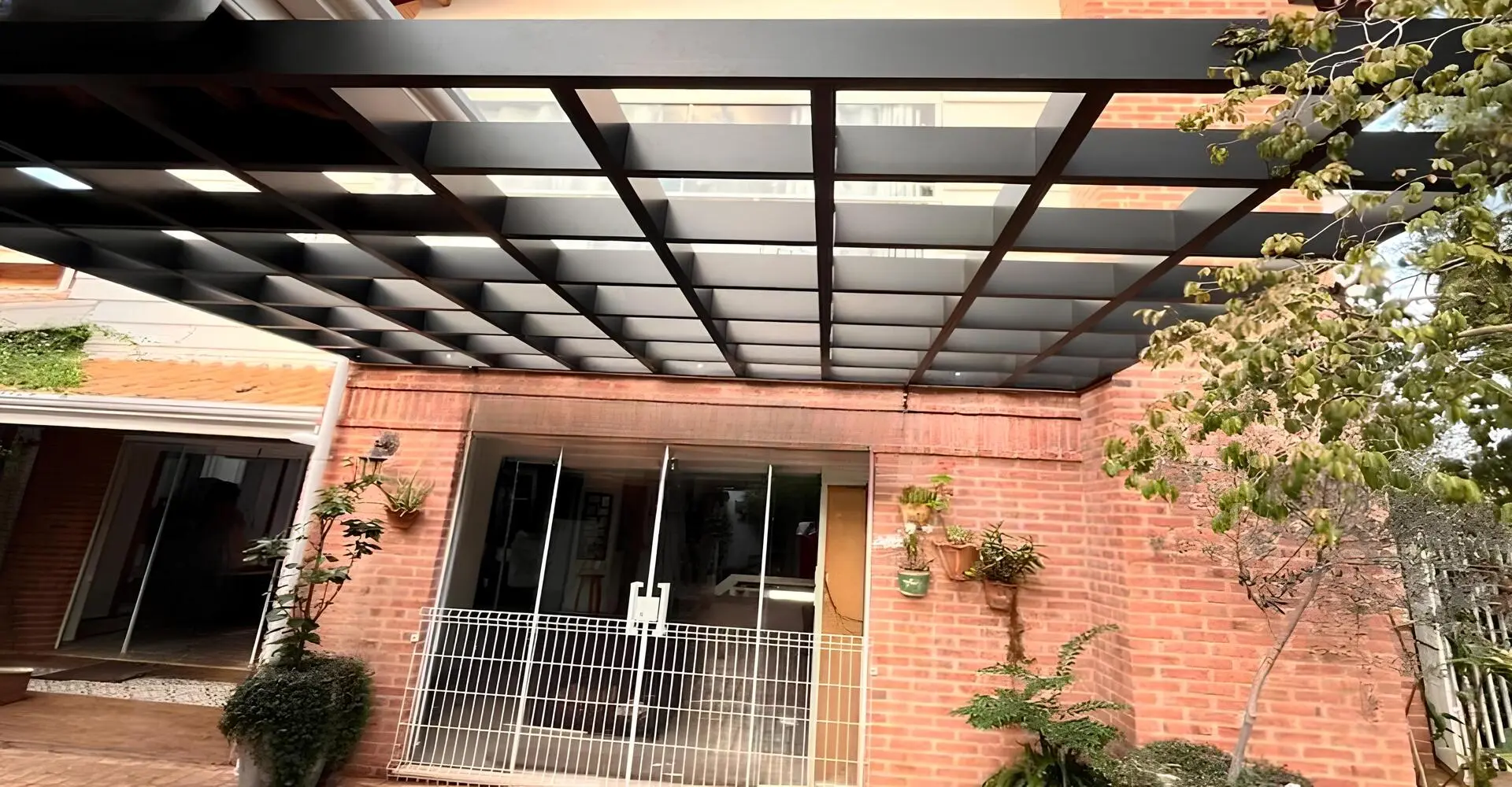 Pergolado de alumínio cruzado instalado em jardim residencial com sombreamento parcial em São Paulo — Toldos Demais